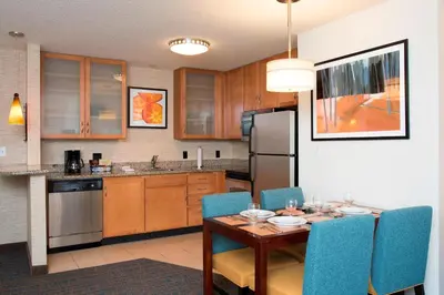 a kitchen with a wooden table and blue chairs at Residence Inn Toledo Maumee in Maumee
