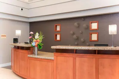 a lobby with a reception counter with flowers on it at Residence Inn Toledo Maumee in Maumee