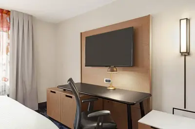 a hotel room with a desk and a tv on a wall at Fairfield Inn by Marriott Warren Niles in Warren