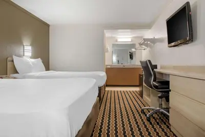 a hotel room with two beds and a desk at Rodeway Inn Sharonville - Cincinnati North in Sharonville