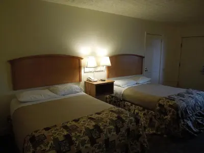 two beds in a hotel room with two lamps at Wildwood Inn in Florence