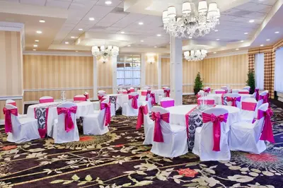 a room with white tables and chairs with pink bows at Ramada by Wyndham Cleveland Independence in Independence