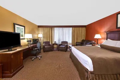a hotel room with a bed and a desk with a television at Ramada by Wyndham Cleveland Independence in Independence