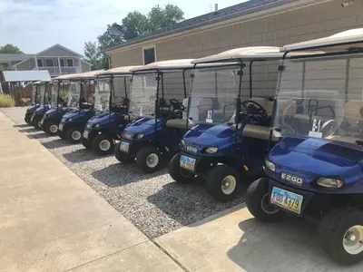 a row of blue golf carts parked next to a building at Bodee's Bungalow Adults Only Couples Only Boutique Hotel in Put-in-Bay