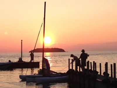 a group of people standing on a dock with a sail boat at Ahoy Inn Guesthouse in Put-in-Bay