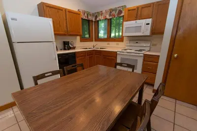 a kitchen with a wooden table and a white refrigerator at Carter Caves State Resort Park in Olive Hill