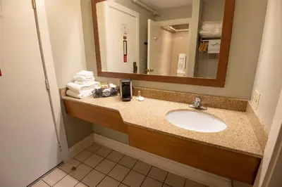 a bathroom with a sink and a mirror and towels at Carter Caves State Resort Park in Olive Hill
