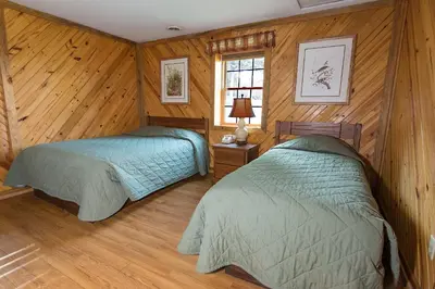 two beds in a room with wooden walls and wood floors at General Butler State Resort Park in Carrollton