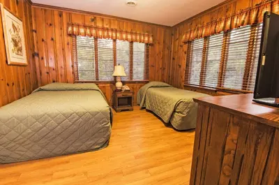 two beds in a room with wooden walls and wooden floors at General Butler State Resort Park in Carrollton