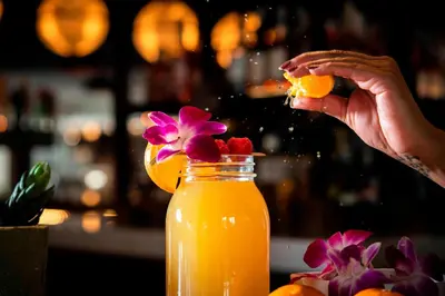 a person squeezing an orange into a jar of orange juice at Courtyard Fort Wayne Downtown at Grand Wayne Convention Center in Fort Wayne