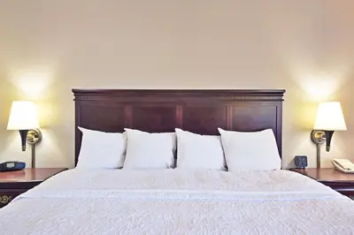 a bedroom with a bed with white pillows and two lamps at Hampton Inn Huntington/Barboursville in Barboursville