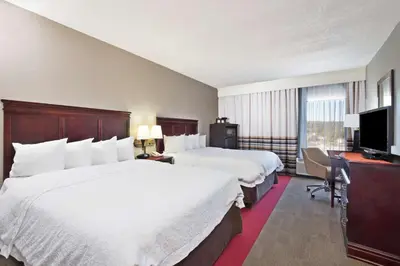 a hotel room with two beds and a desk and a television at Hampton Inn Huntington/Barboursville in Barboursville