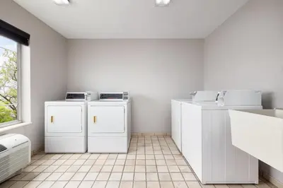 a white laundry room with white appliances and a window at Country Inn & Suites by Radisson, Springfield, OH in Springfield