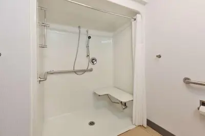 a bathroom with a shower with a bench in it at Hampton Inn Cincinnati Airport-North in Hebron