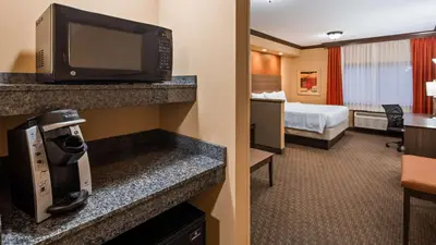 a hotel room with a bed and a room with a television at Best Western Plus North Canton Inn & Suites in North Canton