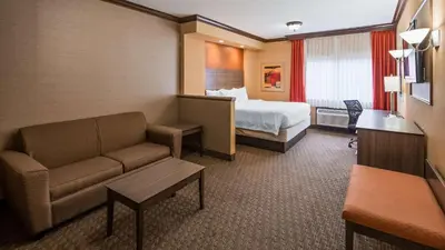 a hotel room with a bed and a couch at Best Western Plus North Canton Inn & Suites in North Canton