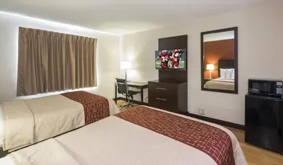 a hotel room with two beds and a flat screen tv at Red Roof Inn Columbus - Ohio State Fairgrounds in Columbus