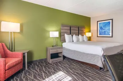 a hotel room with a large bed and a chair at Best Western Dutch Valley Inn in New Philadelphia
