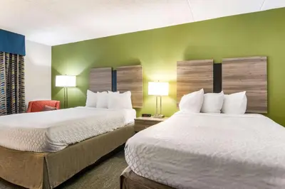 two beds in a room with green walls and two lamps at Best Western Dutch Valley Inn in New Philadelphia