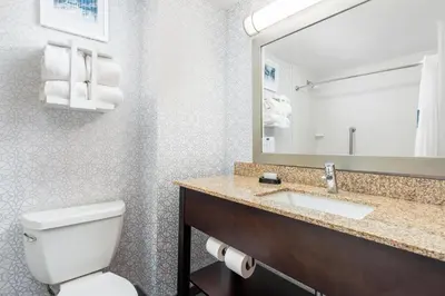 a bathroom with a toilet and a sink and a mirror at Hampton Inn Akron-South in Akron