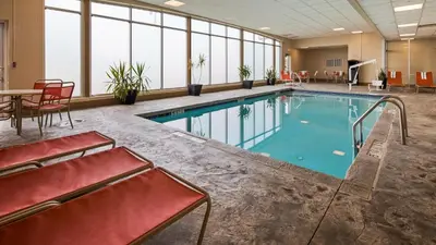 a large swimming pool with chairs and a table in a building at Best Western Airport Inn & Suites Cleveland in Brook Park