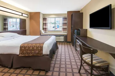 a hotel room with a bed and a flat screen tv at Microtel Inn and Suites North Canton in North Canton