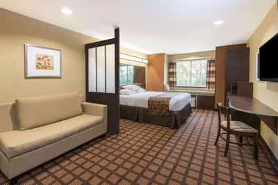 a hotel room with a bed and a couch and a desk at Microtel Inn and Suites North Canton in North Canton