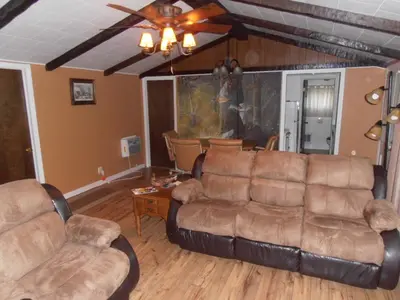 a living room with leather furniture and a ceiling fan at Martin's River Cabin in Dresden