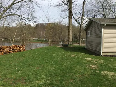 a house on a lawn next to a body of water at Martin's River Cabin in Dresden