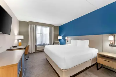 a large white bed in a room with a blue wall at Comfort Inn & Suites Cuyahoga Falls - Akron in Cuyahoga Falls