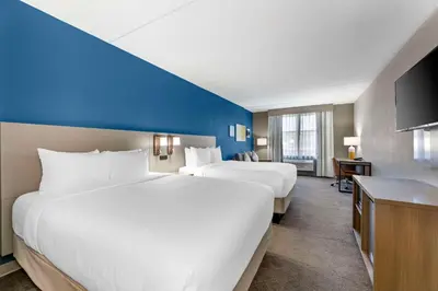 a hotel room with two beds and a blue wall at Comfort Inn & Suites Cuyahoga Falls - Akron in Cuyahoga Falls