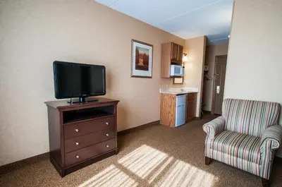 a room with a television on a dresser and a chair at Comfort Inn & Suites Cuyahoga Falls - Akron in Cuyahoga Falls