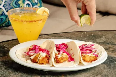 a plate with three tacos on a table with a drink at Residence Inn by Marriott Cincinnati Downtown/The Phelps in Cincinnati