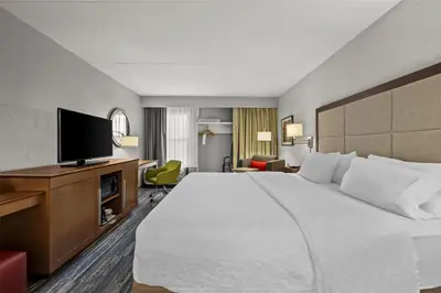 a hotel room with a large bed and a flat screen tv at Hampton Inn Toledo-South/Maumee in Maumee