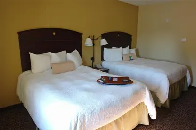 two beds in a hotel room with a tray on the bed at Hampton Inn Gallipolis in Gallipolis