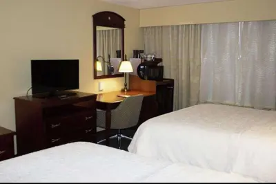 a hotel room with two beds and a desk with a television at Hampton Inn Gallipolis in Gallipolis