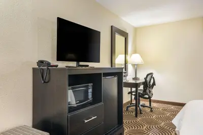 a hotel room with a television and a desk with a chair at Quality Inn & Suites Florence - Cincinnati South in Florence