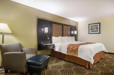 a hotel room with a large bed and a chair at Quality Inn & Suites Florence - Cincinnati South in Florence