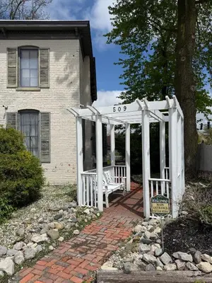 a house with a white porch with a bench at Historic Sion Bass Guest House in Fort Wayne