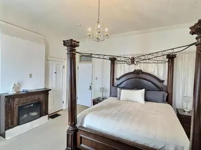 a bedroom with a large bed and a fireplace at Historic Sion Bass Guest House in Fort Wayne