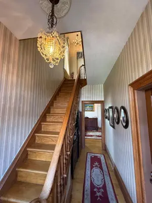 a hallway with stairs and a chandelier at Historic Sion Bass Guest House in Fort Wayne