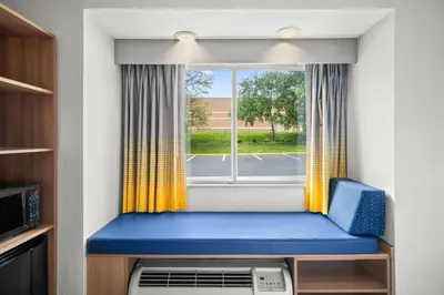 a room with a window with a blue and yellow seat at Microtel Inn by Wyndham Lexington in Lexington