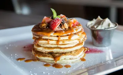 a stack of pancakes with strawberries and syrup on a plate at The Hancock Hotel in Findlay
