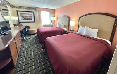 a hotel room with two beds and a bathroom at Fairbridge Hotel Cleveland East in Wickliffe