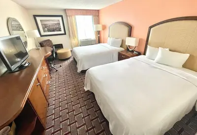 a hotel room with two beds and a flat screen tv at Fairbridge Hotel Cleveland East in Wickliffe