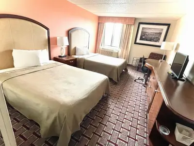 a hotel room with two beds and a desk at Fairbridge Hotel Cleveland East in Wickliffe