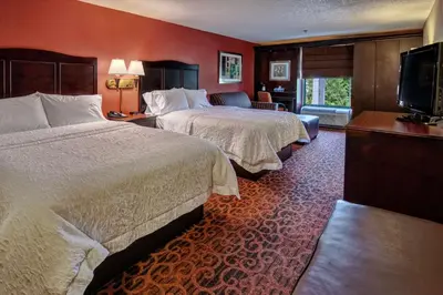 a hotel room with two beds and a flat screen tv at Hampton Inn Ashland in Ashland