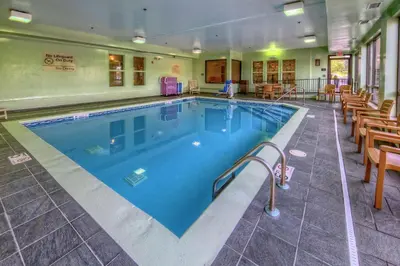 a large swimming pool in a hotel with tables and chairs at Hampton Inn Ashland in Ashland