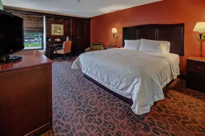 a hotel room with a bed and a flat screen tv at Hampton Inn Ashland in Ashland