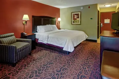 a hotel room with a bed and a chair at Hampton Inn Ashland in Ashland